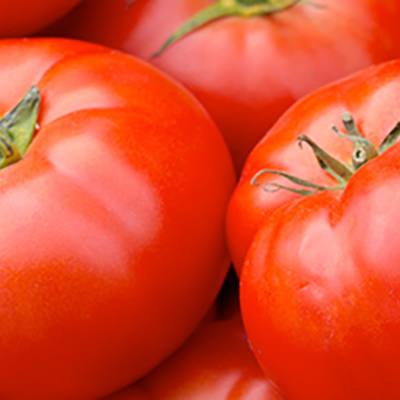 Red beefsteak tomatoes stacked together (detail, upper left)